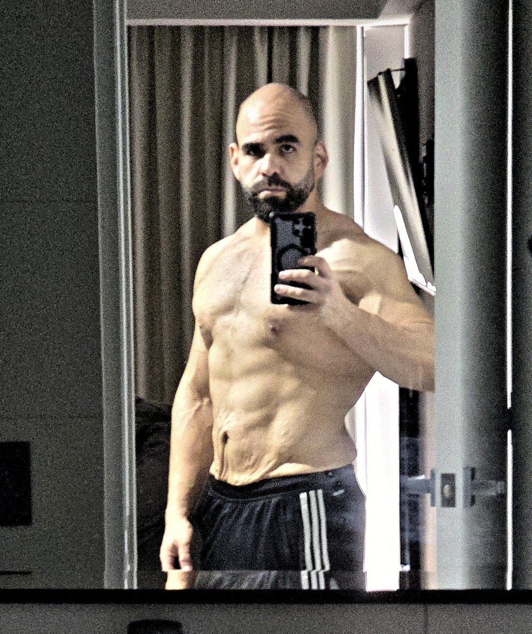 Renzo de pie frente al espejo mostrando su abdomen con piel suelta después de perder 60 kilos